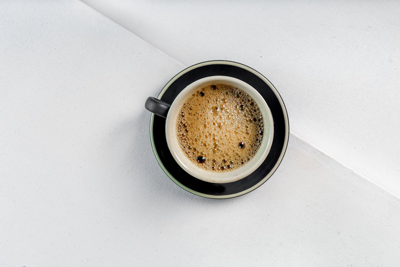 A top view of a classic black coffee cup with foam in a minimalist setting.
