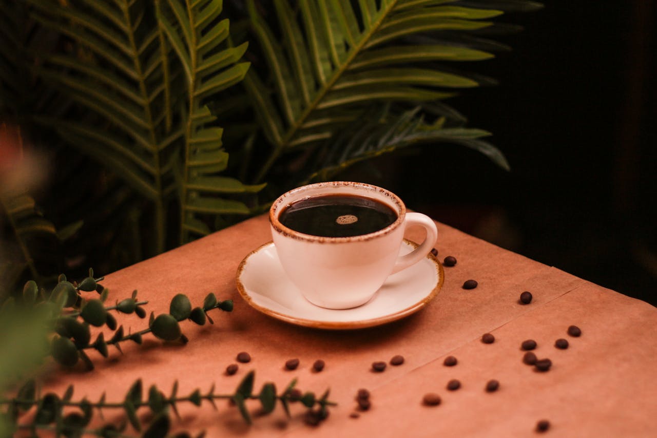 A warm coffee cup on a wooden table with plants and coffee beans, creating a cozy atmosphere.